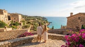 Un couple admirant la vue sur un village méditerranéen en pierre et la mer turquoise en été.