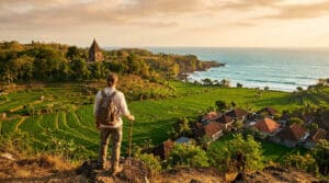Un voyageur avec un sac à dos contemple des rizières en terrasse et un temple balinais au bord de l'océan au coucher.
